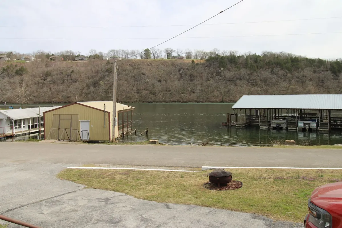 A tranquil waterfront view with dock structures and a gentle hillside backdrop. The calm water and well-maintained docks highlight the prime location for boating or fishing, with scenic vistas making it an ideal spot for morning or sunset outings.