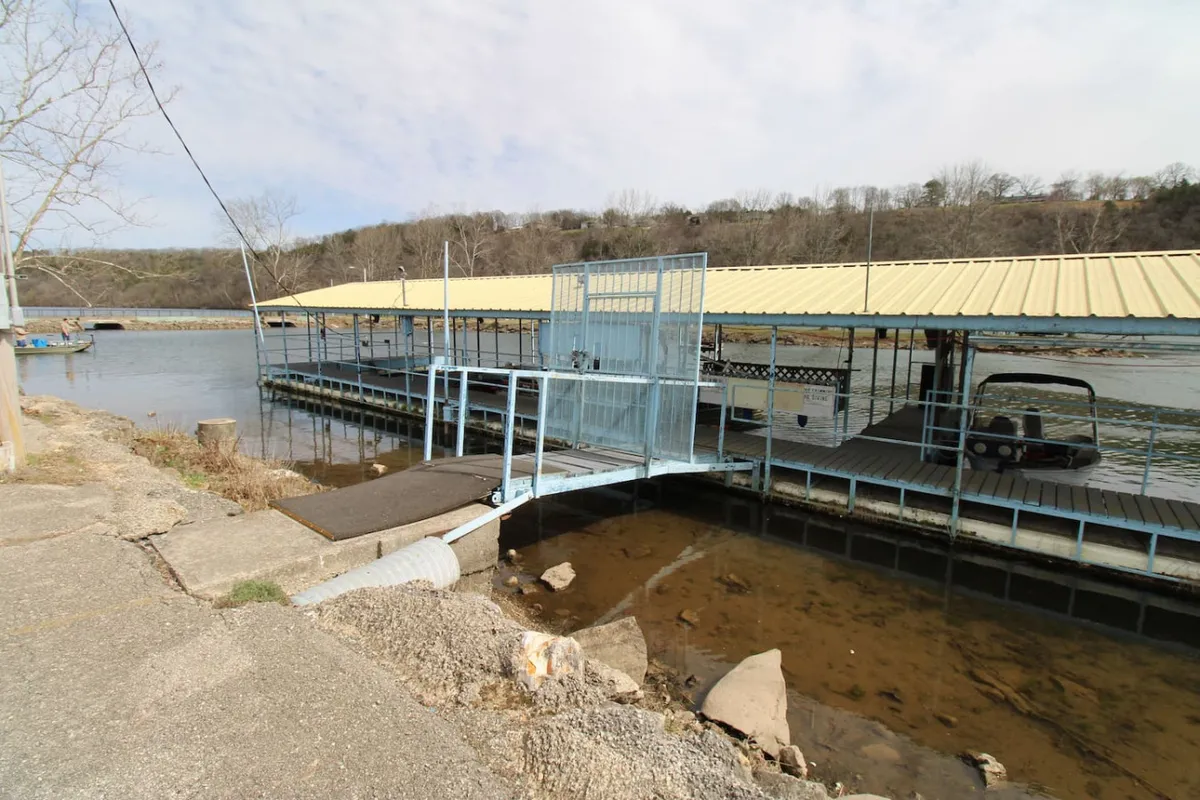 A tranquil dock extends over the water beside a boathouse, with gentle waves and serene surroundings. The scene is peaceful and evokes the ease of stepping out for fishing, boating, or simply relaxing by the lakeshore.